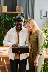 Aufkleber - Two young intercultural employees in casualwear looking at laptop screen while standing by desk and preparing presentation of project