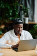 © pressmaster - Young African American businessman concentrating on work with online data while sitting in front of laptop and preparing presentation