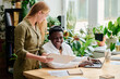 © pressmaster - Happy young African American businessman looking at data shown by blond female colleague consulting with him at meeting