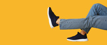 Legs Of Young Man In Stylish Shoes And Jeans On Yellow Background With Space For Text