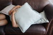 © C Davids/peopleimages.com - Tired, depressed girl sleeping under pillow on sofa in the living room. Woman hide feeling sad or anxiety and problem with depression, mental health and fatigue or fear on couch in the lounge