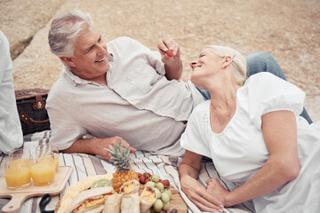 Wall Mural - Food, beach and picnic senior couple dating or on romantic honeymoon date with fruit, snack and drink. Happy, love and romance woman and man or elderly people eating and feed together for anniversary