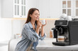 © New Africa - Young woman enjoying fresh aromatic coffee near modern machine in kitchen