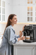 © New Africa - Young woman preparing fresh aromatic coffee with modern machine in kitchen