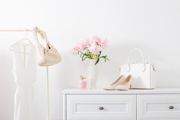 white dresser with clothes and flowers in white room