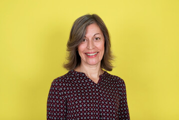 Portrait of a smiling middle-aged woman on a yellow background