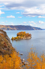 Beautiful Bright Autumn Landscape Of Baikal Lake And Shamansky Cape During Leaf Fall. Yellow Birch, Aspen And Red Mountain Ash Trees Adorn The Wooded Peninsula. Natural Background
