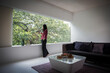 © Caia Image - Young woman drinking tea at window in modern living room