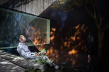 Serene Man Sitting In Sunlight In Courtyard
