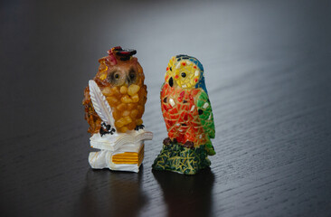 A pair of souvenir owl figurines.  Spanish one in Gaudi style, other one Baltic, inlaid with amber stones.