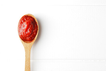 A spoon full of tomato sauce on a white wooden background with space for text. Ingredient Tomato Sauce for Cooking