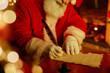 Closeup of traditional Santa Claus writing letter by fireplace on Christmas eve, copy space