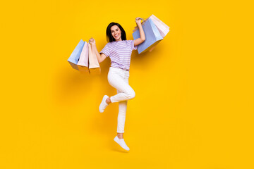 Canvas Print - Photo of gorgeous cute sweet woman wear striped t-shirt white trousers sneakers jumping hold packages isolated on yellow color background