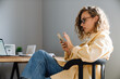 © Drobot Dean - Young curly serious woman in glasses with phone