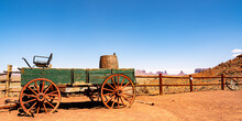 Old Wagon With The Monument Valley Silhouette In The Distance.