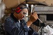 © Seventyfour - Side view portrait of female worker operating machine units in industrial workshop and wearing protective gear