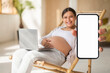 © Prostock-studio - Pregnancy Tracker App. Pregnant woman showing blank smartphone while resting in chair