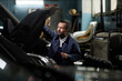 © Seventyfour - Side view portrait of mature car mechanic repairing trucks in garage with accent light, copy space