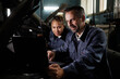 © Seventyfour - Portrait of two smiling mechanics repairing truck and using laptop in garage with accent light