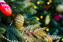 Golden Cone And Red Mitten On A Green Branch Of An Artificial Christmas Tree
