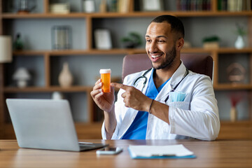 Wall Mural - Friendly black doctor working online, having video chat with patient