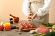 © Pixel-Shot - Female chef cooking meat balls at table near beige wall