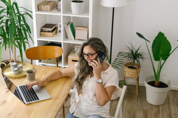 Happy woman using laptop and talking on the phone