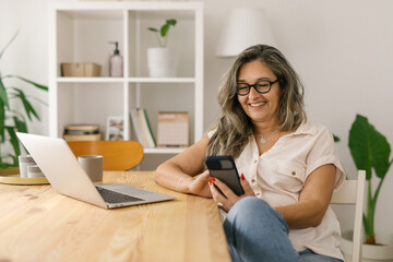 Happy female using social media via smartphone at home