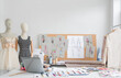 Workplace of dressmaker and designer seamstress tailor with the dummy mannequin, sewing machine, laptop, thread, sketches, and other in fashion design studio.