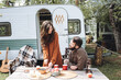 Young beautiful loving couple travelling across country in the van. Millennial man and woman in a travel camper. Cozy atmosphere, vacations vibe. Drinking tea, playing guitar