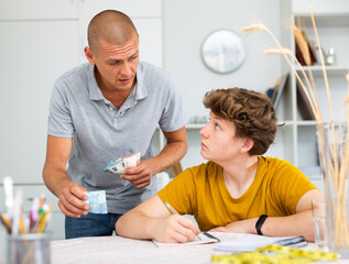 Father and son counting money while sitting at the table at home