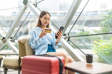 Young asian beautiful female lady making a payment for an online shopping purchase via her smart phone easily and successful while sitting in a cafe