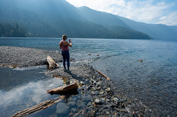 Wall Mural - Young woman enjoying view on shore of Lake Crescent in Olympic National Park, Washington on sunny autumn afternoon..