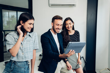 Wall Mural - Group of businesspeople talking and using a digital tablet together, Smiling business team having a discussion in an office