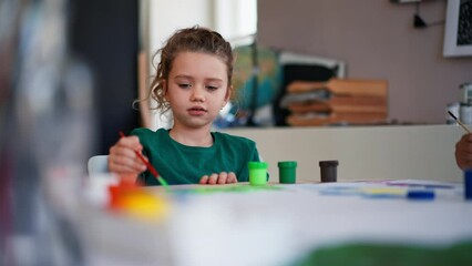 Wall Mural - Happy little girl painting picture during creative art and craft class at school.