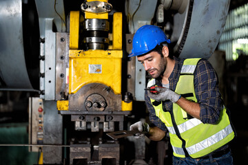 maintenance engineer working in steel factory shop checking operation compression machine and radio walkie talkie to team member