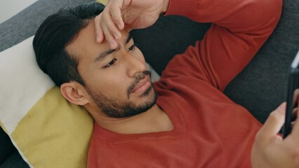 Poster - Stress, shock and man texting on phone, shocked by bad news, scam alert or a breakup text. Confused, unhappy and worry with young male surprised by app message, feeling puzzled and nervous in home