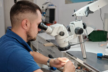 Technician In Dental Lab Working Under A Microscope