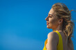 closeup sideview of happy smiling attcative caucasian woman in yellow sundress looking side against ultramarine sky