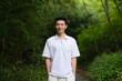 Asian young man at green bamboo forest, smiling at camera