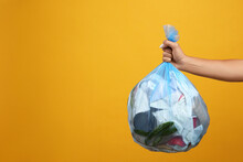 Woman Holding Full Garbage Bag On Yellow Background, Closeup. Space For Text