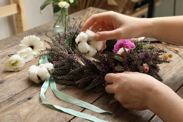 Wall Mural - Florist making beautiful autumnal wreath with heather flowers at wooden table, closeup