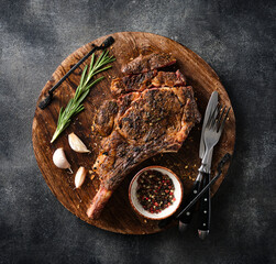 Wall Mural - Freshly grilled Tomahawk steak on a wooden cutting board, BBQ food, top view, grey background.