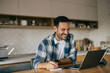 © bnenin - Smiling businessman working from home, writing notes in his notebook.