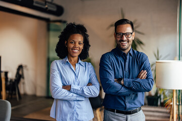 Portrait of a two business people, hands crossed, smiling for the camera.