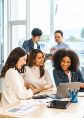 Young and successful mixed race, asian business people working on project together, sitting at table in boardroom.