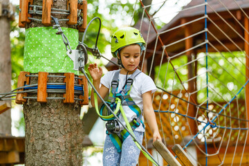 Adorable little girl enjoying her time in climbing adventure park on warm and sunny summer day