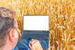 © ARVD73 - A businessman with a laptop in her hands works in wheat field, communicates and checks the harvest.Man farmer at sunny day with computer.Agricultural business concept.blank white screen.Mockup.