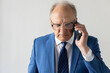 Portrait of frowning mature businessman talking on mobile phone. Senior manager wearing formalwear and eyeglasses answering call. Mobile communication concept