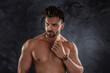 © neonshot - Muscular man posing shirtless on a dark background. Handsome male model with beard.